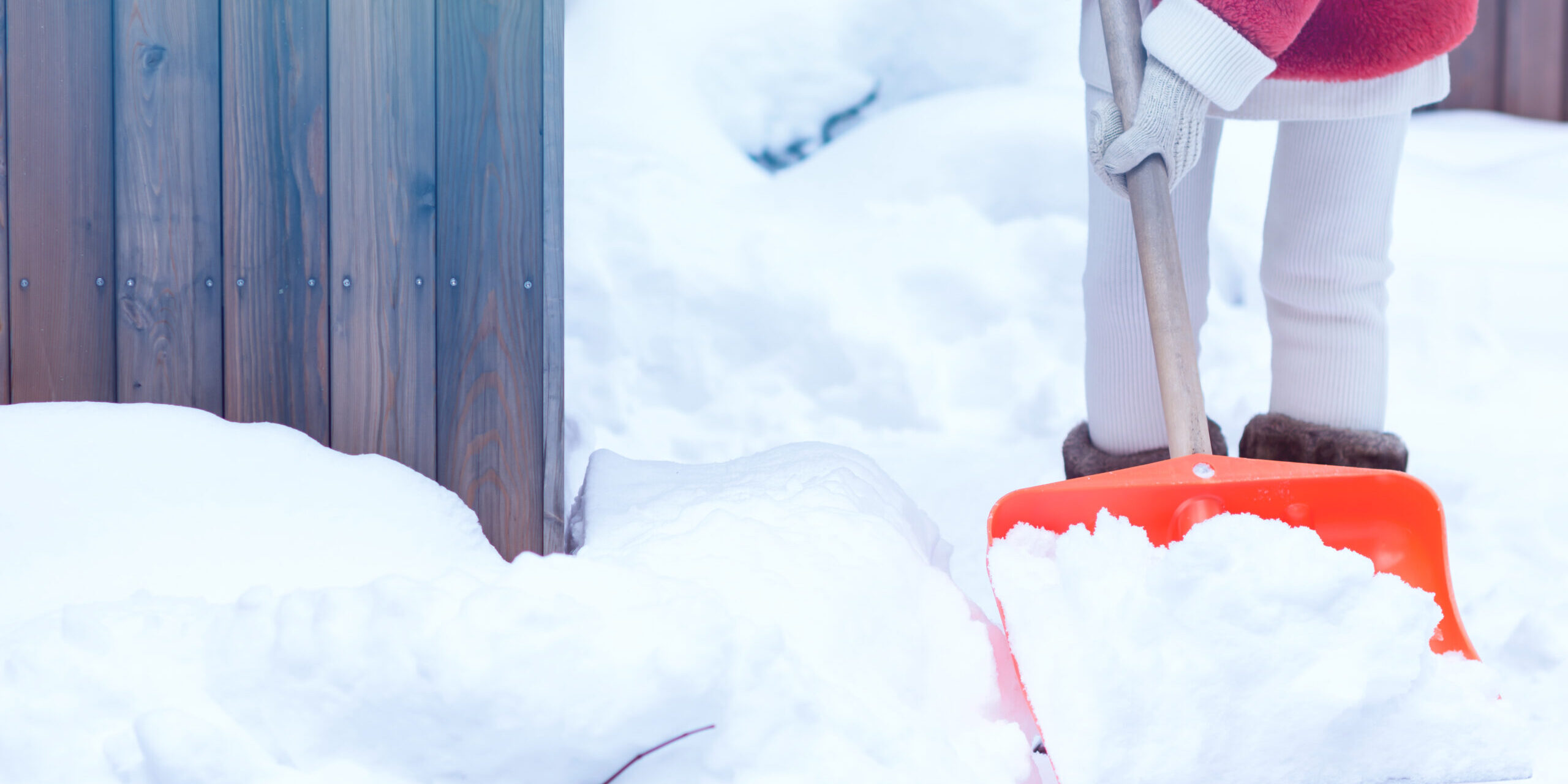 Woman in red faux fur coat keeps shovel with snow, she is clean